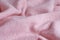 Soft knitted fabric made of cashmere with large folds, a detail of clothes. pink fabric texture