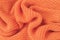 Soft knitted fabric from orange fluffy yarn.