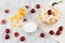 Soft light breakfast with golden corn flakes, ripe cherries, powdered sugar on white wood board top view.