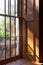 Soft light coming in through a deep window with wood paneling and window bars, view onto garden