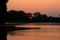 A soft orange sunrise over a calm lake overgrown with water lilies