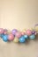 A soft pastel balloon garland against a light lemon yellow background