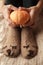 Soft photo of woman legs in cute funny bear brown socks on the bed with little decorative pumpkin, monochrome halloween fall autum
