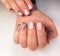 Soft pink gel polish on short nails with a brilliant design. Professional manicure in camouflage color and silver design.