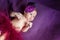 Soft portrait of peaceful sweet newborn infant baby lying on bed while sleeping in purple blanket