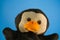 Soft puppet toy on blue background. Concept of puppet show. Close-up of puppet penguin.