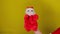 Soft puppet toy of santa claus on hand. Santa claus puppet on yellow background. Close up. Concept of puppet show and