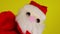 Soft puppet toy of santa claus waves hand. Close-up of santa claus puppet on yellow background. Concept of puppet show