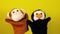 Soft puppet toys on hands on yellow background. Concept of puppet show. Close-up of hands with puppet monkey and penguin