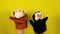 Soft puppet toys on hands on yellow background. Concept of puppet show. Close-up of hands with puppet monkey and penguin