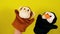 Soft puppet toys on hands on yellow background. Concept of puppet show. Close-up of hands with puppet monkey and penguin