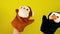 Soft puppet toys on hands on yellow background. Concept of puppet show. Close-up of hands with puppet monkey and penguin