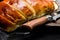 Soft roasted wheat bread above a wooden board with a knife on dark background