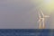 Soft seascape. Wind, sea and solar power renewable energy represented by offshore wind turbines illuminated by bright sunshine