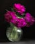 Soft selective focus, photo in motion, bouquet of dark red lilac tulips in glass vase on dark background