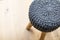 Soft stool made of wool on a light-colored wooden parquet. Stool chair with gray knitted fabric cover. Interior furnishing