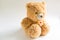 Soft Teddy bear with long light brown fur and a red heart on a scarf around his neck. Valentine`s day gift, children`s toy. White