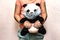 Soft toy panda in a disposable medical mask in children`s hands. Coronavirus epidemic concept. Personal hygiene for kids