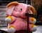 A soft toy of a pink elephant sits on a chair in a street courtyard