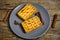 Soft waffles in plate loaded with honey, on wooden table