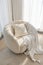 a soft white comfortable round armchair with a pillow in a gentle cozy bright apartment with huge panoramic windows with sunlight