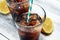 Softdrink with ice cubes, lemon and straw in glass