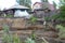 Soil destruction landslide under a wooden house ravine with garbage in the village