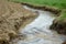 soil erosion on farmland with clear water turning muddy downstream