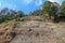 Soil erosion in the highlands. Landscape mountain with soil cracked. Rock outlier on background of mountains with forests, which a