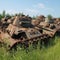 Soil pollution after war, garbage, scrap metal on field. Heap of many old broken rusty panzers under blue summer sky