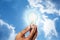 Solar energy. Man holding glowing light bulb against blue sky with clouds, closeup