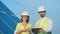 Solar engineers talk while walking on a roof with a tablet.