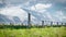 Solar farm of photovoltaic panels on a beautiful green meadow with wind turbines in the background