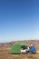 The solar panel attached to the tent. The man sitting next to mobile phone charges from the sun.