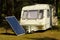 Solar panel in a camping with old caravan on the river bank