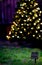A solar panel in front of a Christmas tree with solar powered Christmas lights at dusk with recycle symbol bokeh