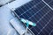 Solar panels of a photovoltaic system on a roof are cleared of snow with a broom