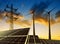 Solar panels with wind turbines and electricity pylon at sunset.