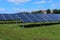 Solar power plant, blue solar panels on a field with fresh green grass under blue sky