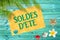 Soldes d`ete meaning summer sale in French written on yellow sign, blue wood planks, seashells, beach and palm tree backgroun