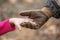 A soldier in the army uniform and gloves, holding out his hand a little girl.