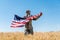 Soldier in cap and uniform holding american flag in golden field