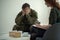 Soldier hiding his face in his hands while talking to a psychiatrist during therapy