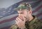 Soldier hiding his mouth with his hands in front of american flag