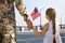 Soldier and his little daughter with American flag holding hands outdoors, back view. Veterans Day in USA