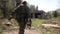 Soldier in military uniform with weapon running on background of ruined house.