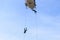 Soldier rappelling from helicopter in blue sky with blur propeller