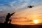 Soldier trying to shoot down reconnaissance drone against the backdrop of a sunset.