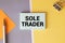 SOLE TRADER, text on white notepad on craft background