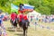 Solemn entry of a group of horse racing with flags in the meadow of the festival